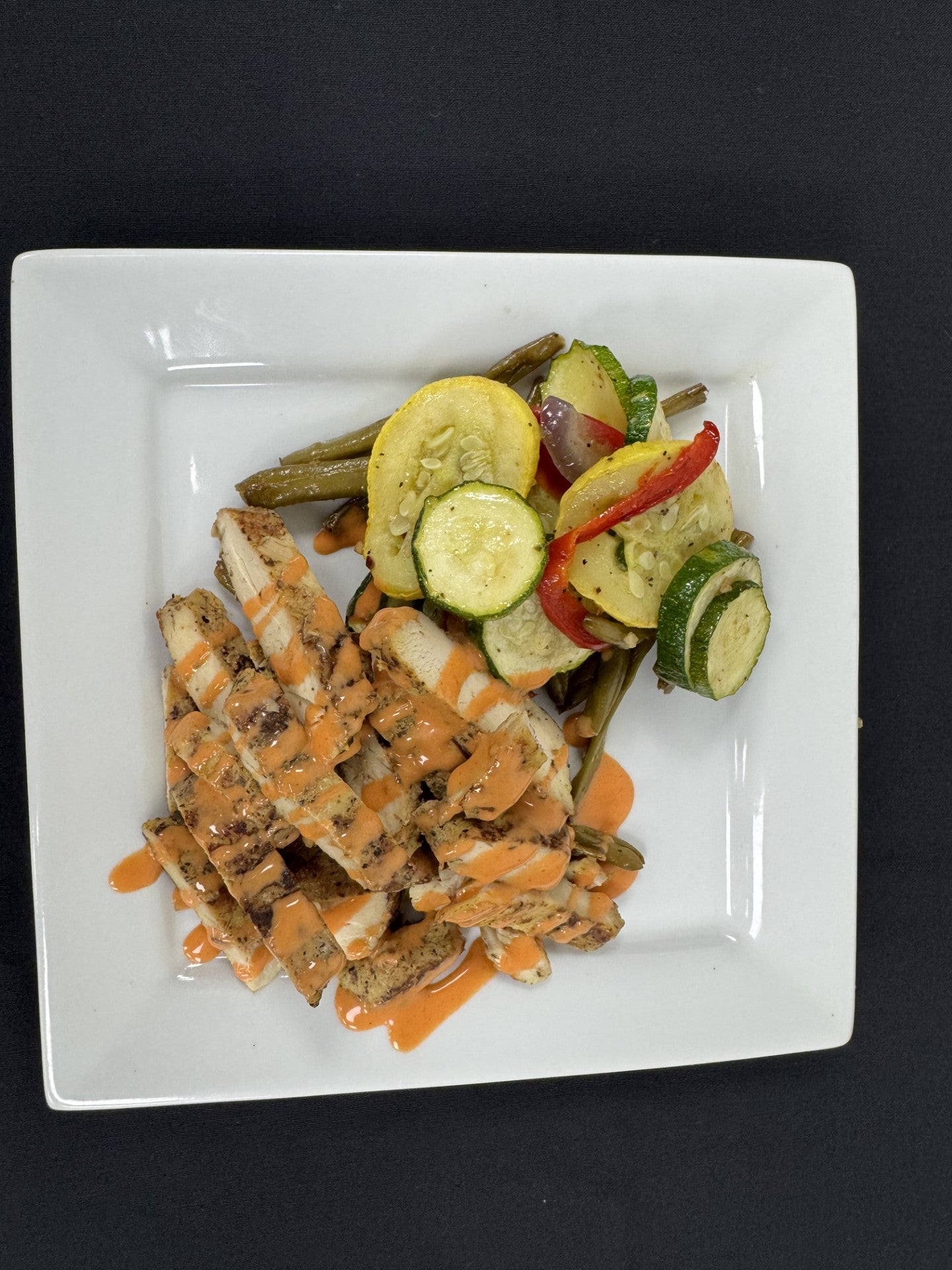 Roasted vegetables and a side of sliced chicken breast drizzled with a buffalo ranch sauce